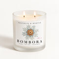 Bombora double-wick candle burning in a frosted white glass jar with blue and orange marine label artwork.
