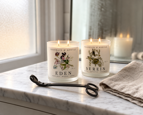 Black candle wick trimmer beside lit Franklin & Myrtle Eden and Serein candles