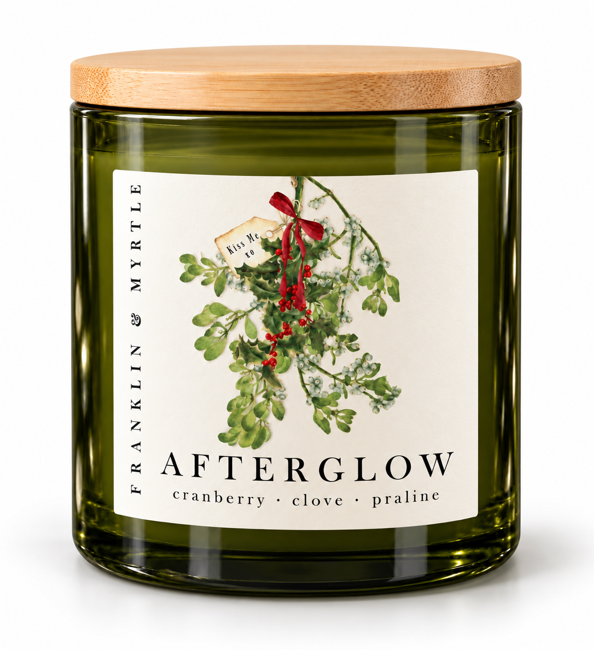 Afterglow candle in an olive green glass jar with a bamboo lid. The label features mistletoe tied with a red ribbon and the notes cranberry, clove, and praline.