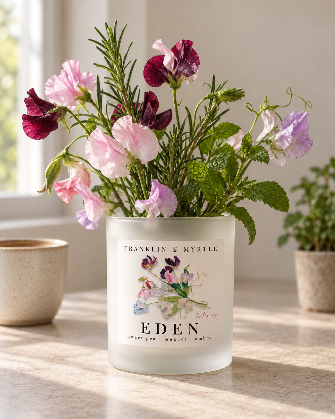 Eden frosted glass candle jar repurposed as a vase with colorful sweet peas, rosemary, and fresh mint.