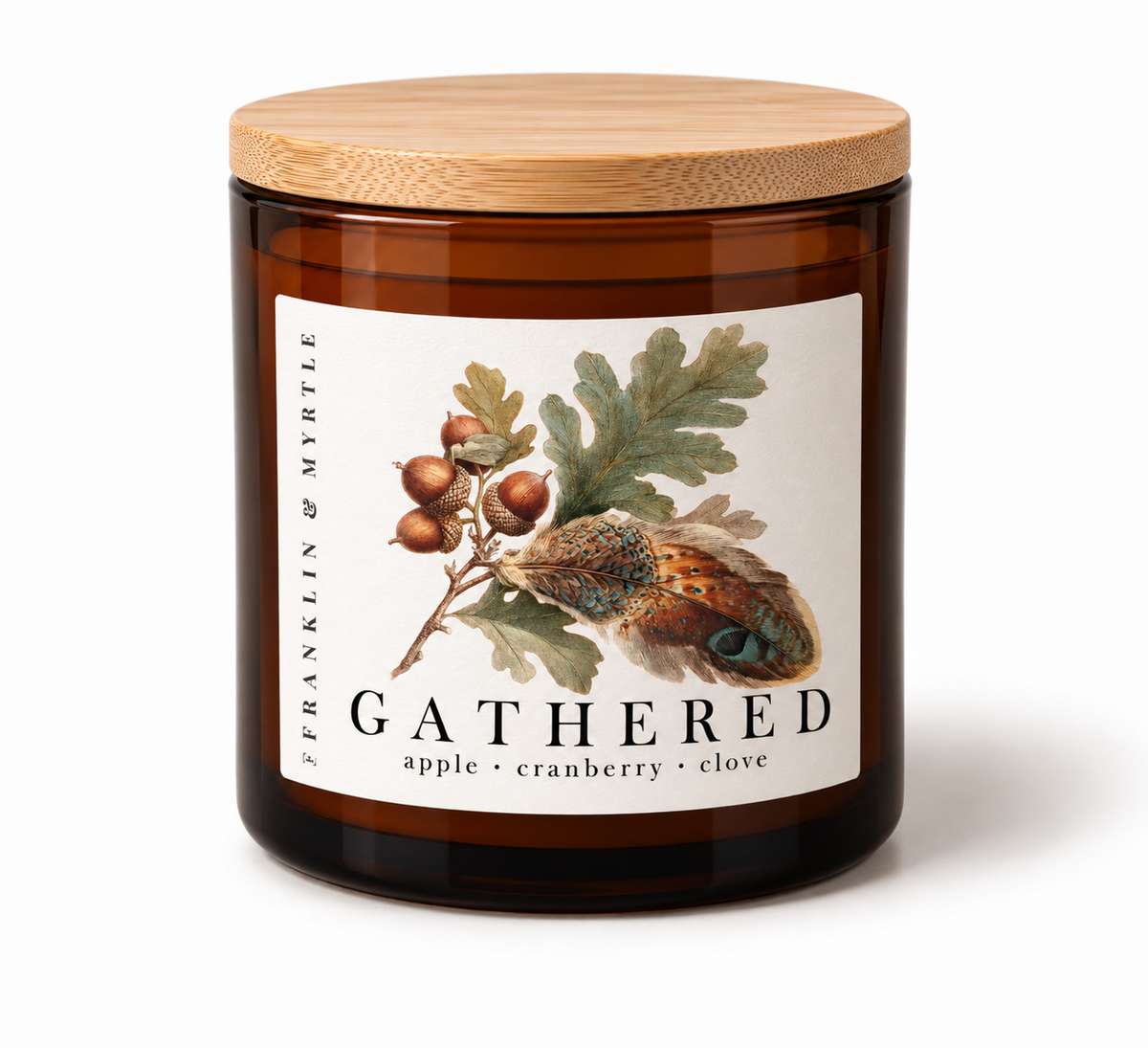 Gathered candle in an amber glass jar with a bamboo lid. The label features oak leaves, acorns, and a feather above the notes apple, cranberry, and clove.