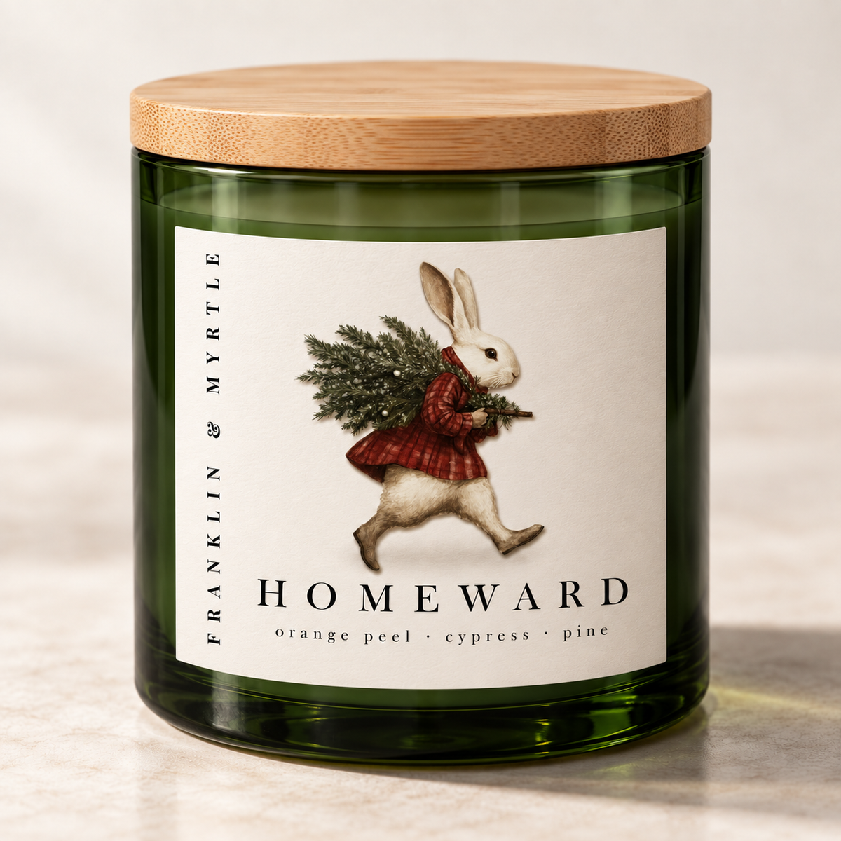 Homeward candle in a dark green glass jar with a bamboo lid and a label showing a rabbit carrying pine branches