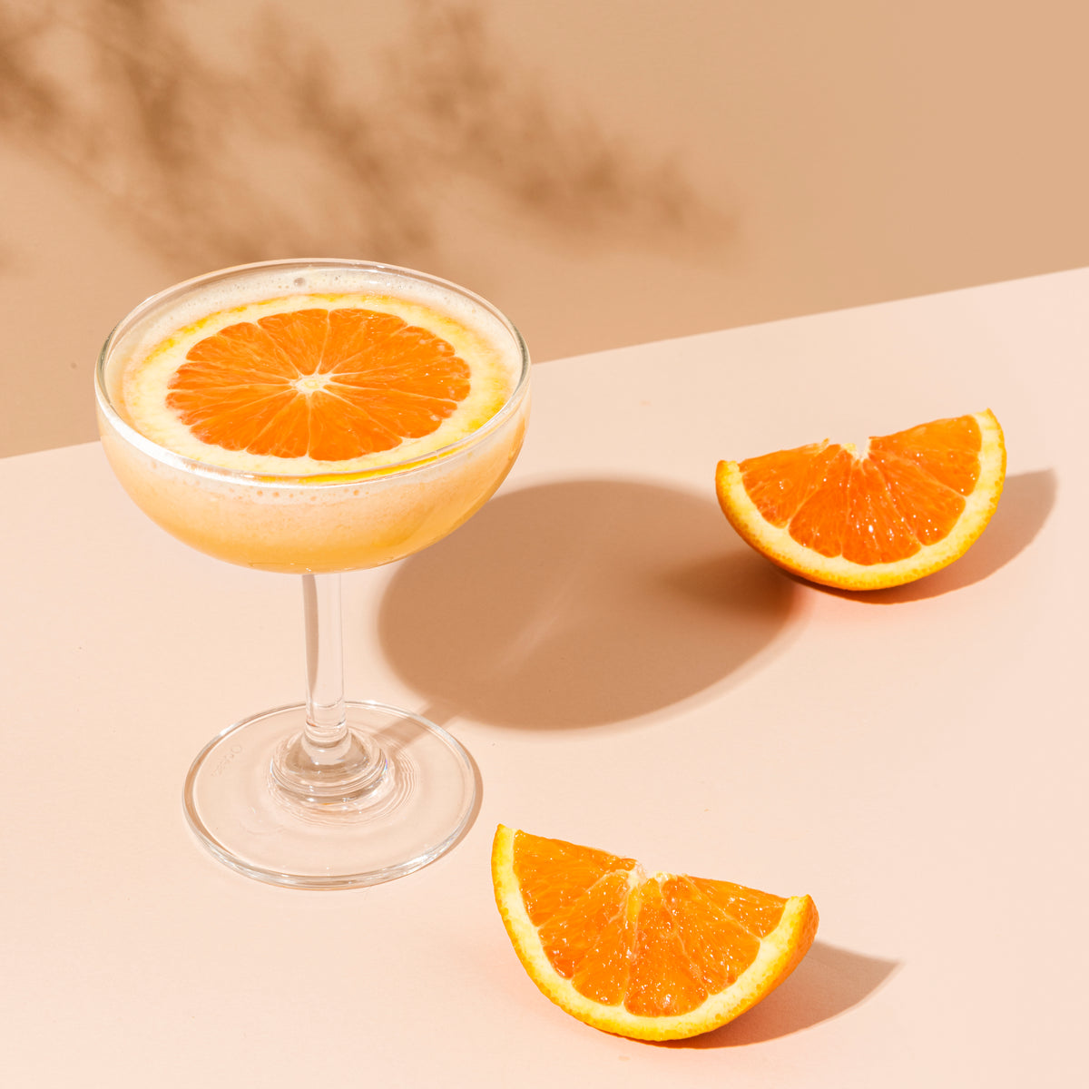 Frothy orange drink in a coupe glass with fresh orange slices, evoking the bright citrus character of Soleil.