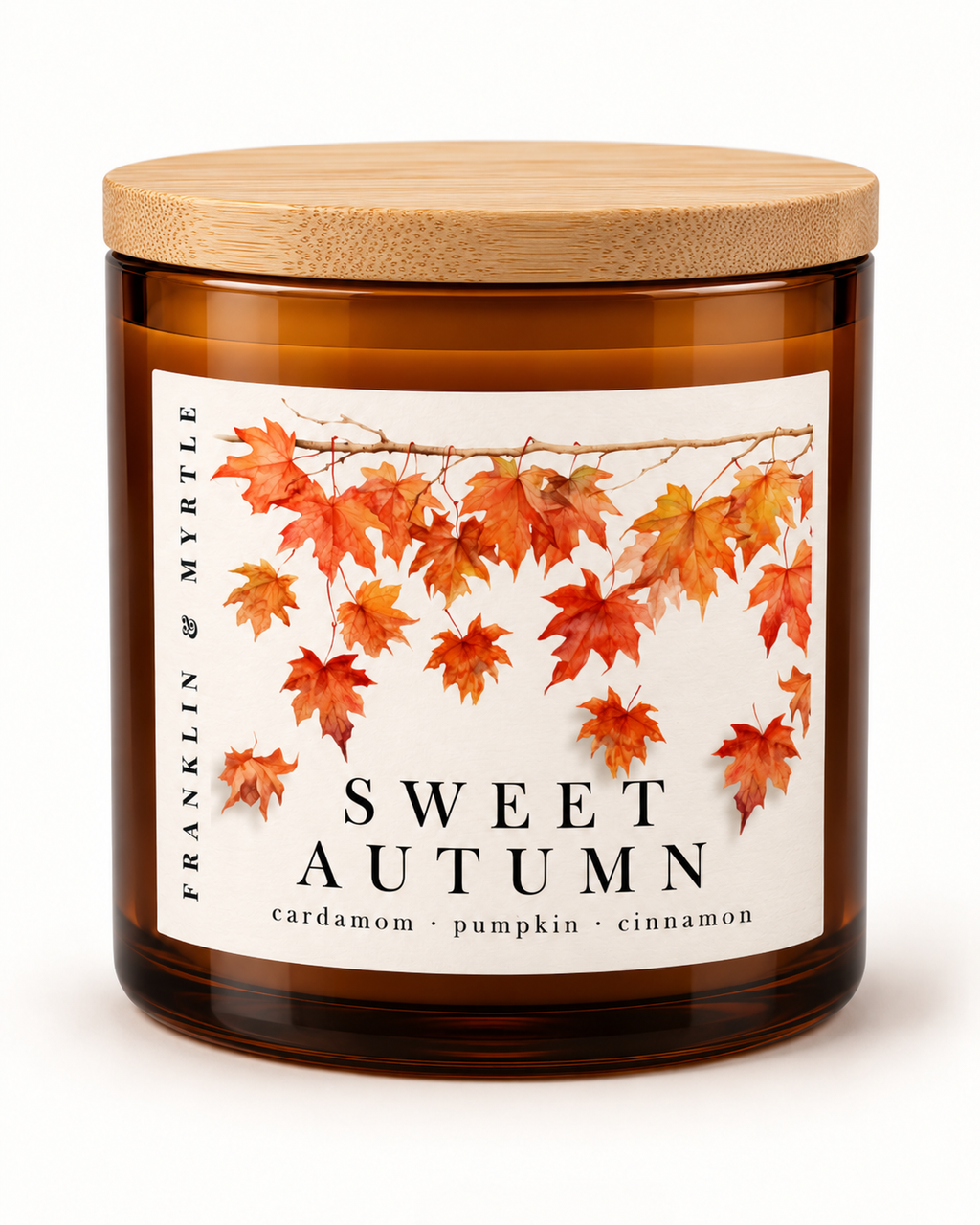 Sweet Autumn candle in an amber glass jar with a bamboo lid. Its label shows falling orange and red leaves above the notes cardamom, pumpkin, and cinnamon.