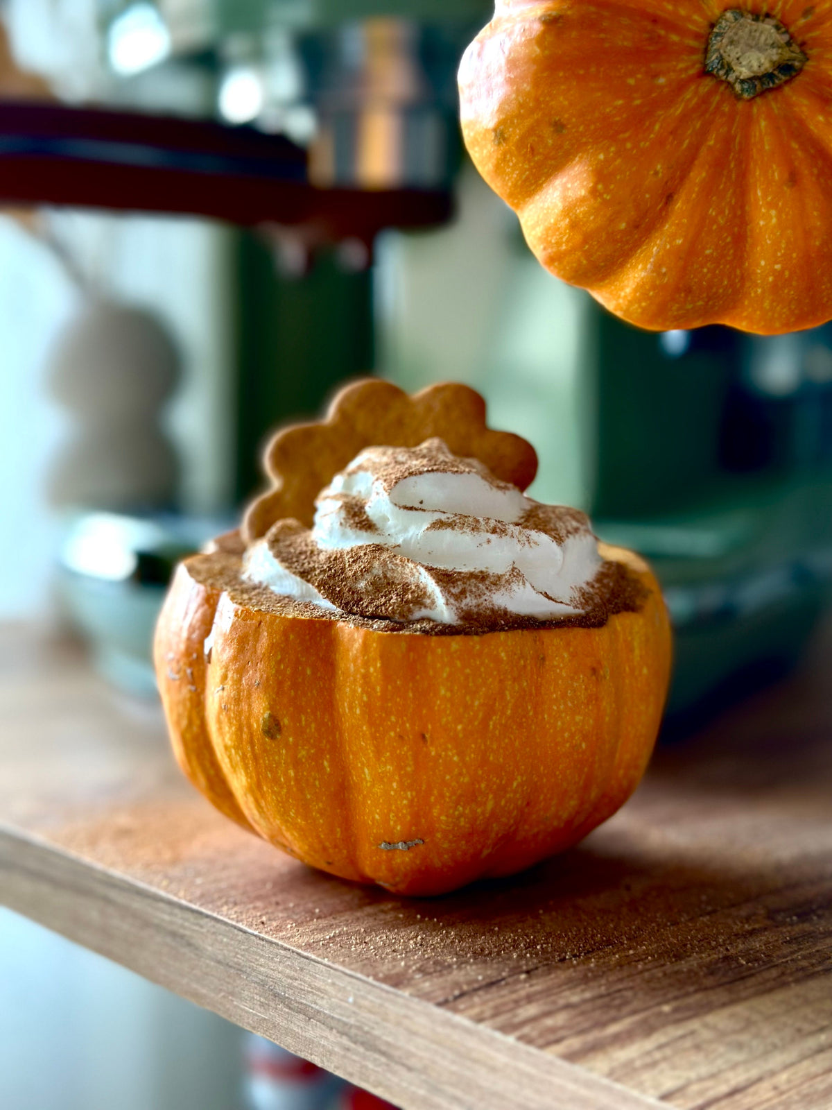 Small pumpkin filled with a whipped dessert and dusted with spice on a wooden table.